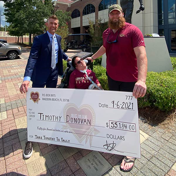 Dillan Gibbons posing with Timothy Donovan while holding a large check with the amount of $55,184