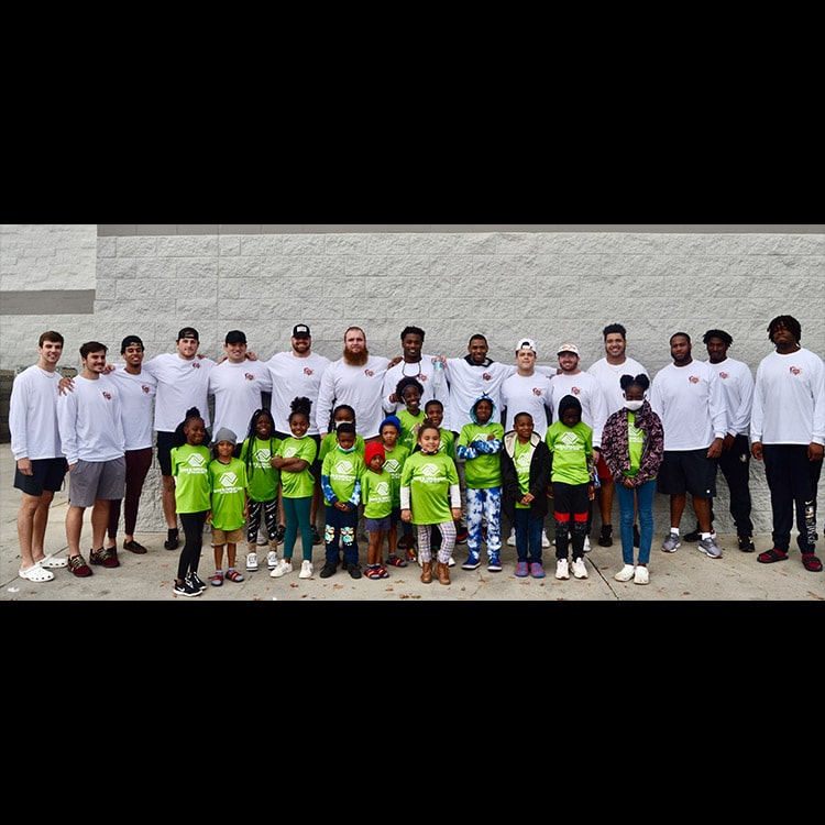 Christmas Initiative group photo of children from the Boys & Girls Club along with players in the background