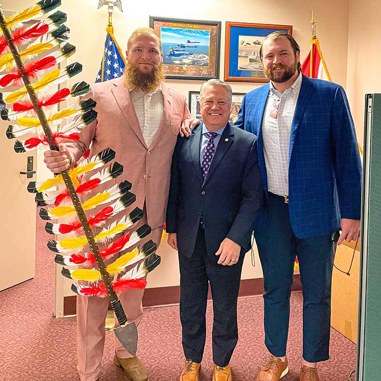 Dillan Gibbons posing with colleagues holding the FSU spear
